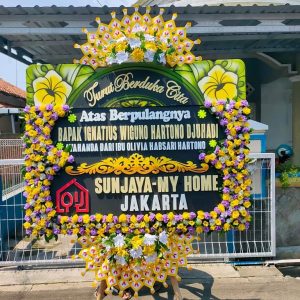 Karangan bunga duka dengan pita hitam dan pesan belasungkawa