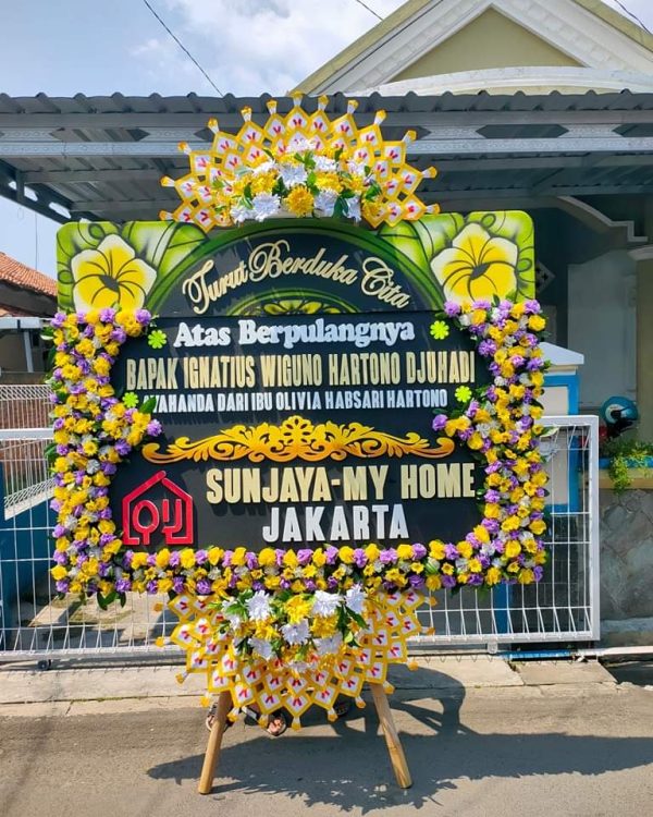 Karangan bunga duka dengan pita hitam dan pesan belasungkawa